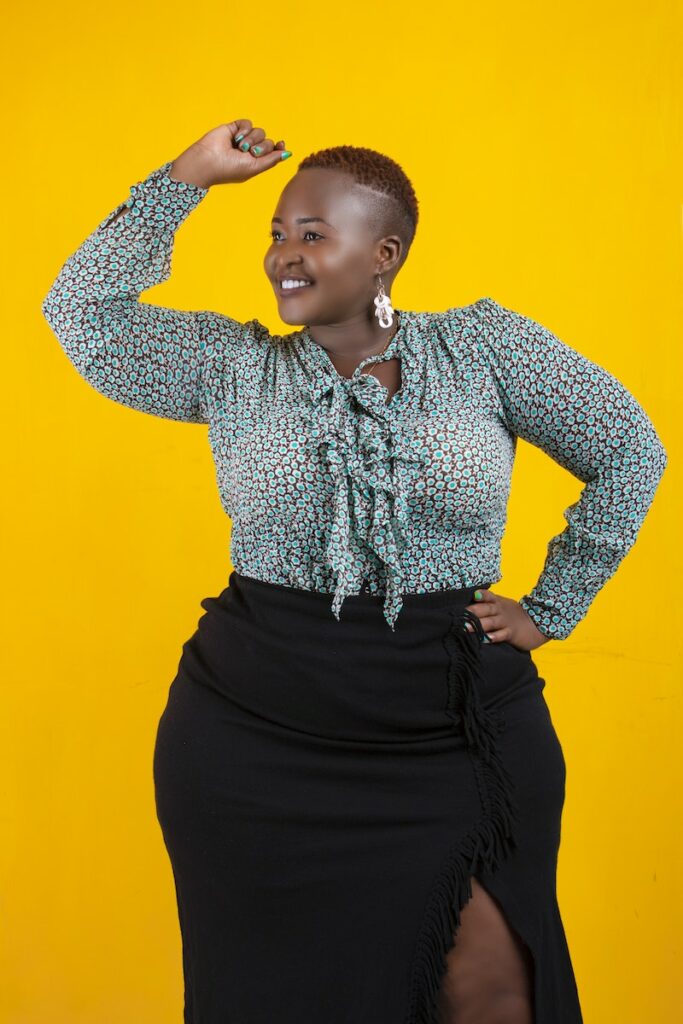 Cheerful black overweight woman with raised arm in studio